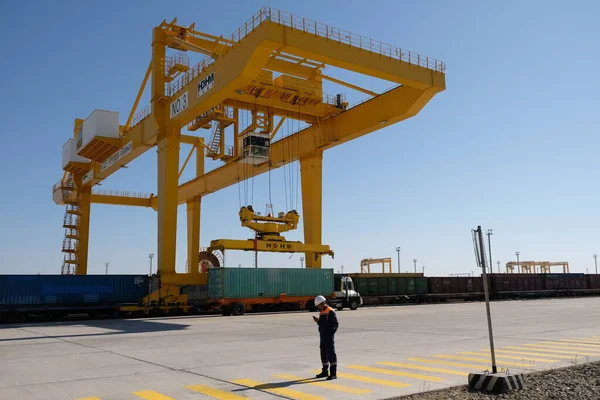 Khorgos / Kazakistan - 10.06.2018: Lojistik merkezinde konteynırlar boşaltılıyor. Makineler ve turnalar metal kutuları sürüklüyor.