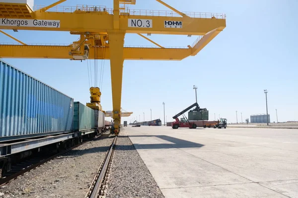 Khorgos / Kazakistan - 10.06.2018: Lojistik merkezinde konteynırlar boşaltılıyor. Makineler ve turnalar metal kutuları sürüklüyor.