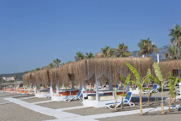 Tumbonas vacías y gazebos con techos de sal en la playa de Turquía —  Fotos de Stock