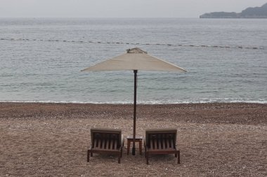 İki şezlong ve şemsiye ile küçük tablo