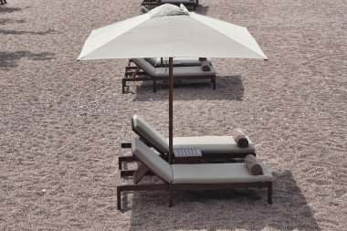 İki şezlong ve şemsiye ile küçük tablo