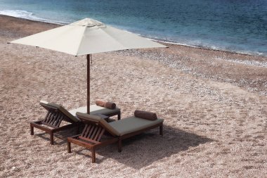 İki şezlong ve şemsiye ile küçük tablo