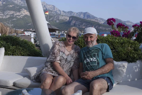 Счастливая зрелая пара в отпуске улыбаются, сидя на б — стоковое фото
