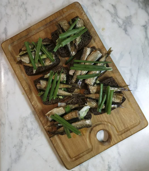 Sandwiches con espadines sobre pan marrón, decorados con cebolla verde — Foto de Stock