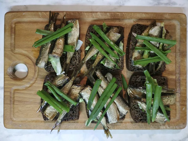 Sandwiches con espadines sobre pan marrón, decorados con cebolla verde — Foto de Stock