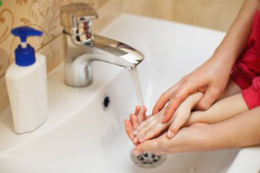Çocuklu bir anne koronavirüsten ellerini yıkar. Mikroplardan ve virüslerden ellerini yıkamak için hijyen.