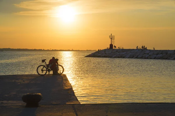 Ein Mann mit einem Fahrrad auf der Seebrücke bei Sonnenuntergang. — Stockfoto