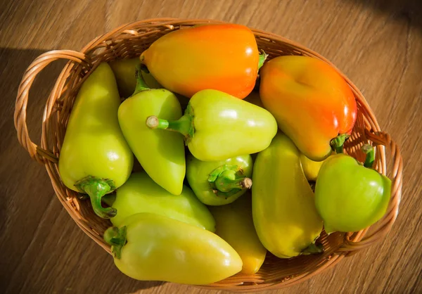 Fresh pepper in a wicker basket on a wooden table. — Stock Photo, Image