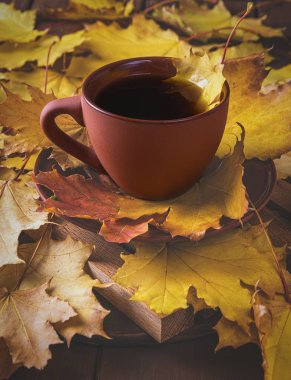 Sonbahar, sonbahar yaprakları, ahşap masanın üstünde sıcak bir fincan kahve.