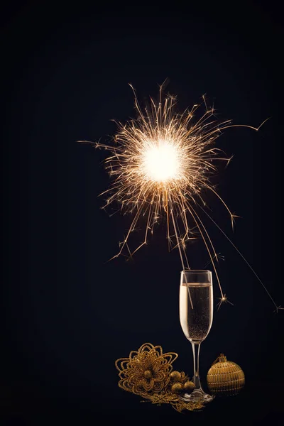 Champagne glass with lit sparkler against a dark background — Stock Photo, Image