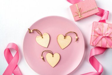 Kalpler tabakta, pembe kurdele ve hediyeler beyaz bir masada..