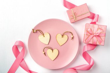 Kalpler tabakta, pembe kurdele ve hediyeler beyaz bir masada..