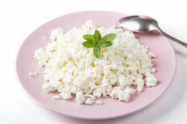 Beyaz arka planda izole edilmiş pembe tabakta süzme peynir.