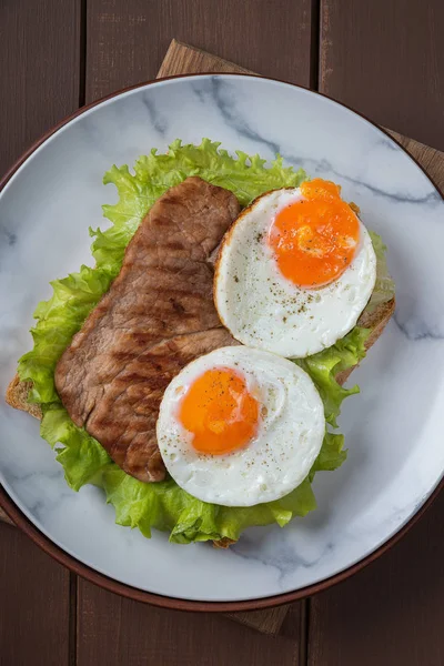 Kahvaltı için kızarmış yumurta ve biftek tabakta ve kırsal masada. — Stok fotoğraf