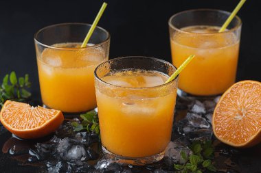  Dilimlenmiş mandalinalı mandalina kokteylleri, buz, siyah ahşap bir masada nane.