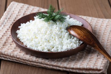 Ahşap bir masada ahşap bir tabakta süzme peynir.