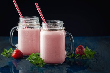  Siyah bir masada lezzetli çilekli milkshake ile cam bardaklar.