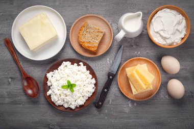 Farklı türde süt ürünleri, ahşap bir masada ekmek ve yumurta.