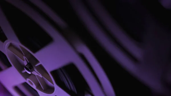 Old 8mm film projector playing in the dark room with violet light. Close-up of a reel with a film. — Stock Photo, Image