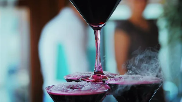 Camarero vertiendo vino tinto o champán en vasos con nitrógeno líquido para la fiesta. Joven vierte vino en la pirámide de las copas . —  Fotos de Stock