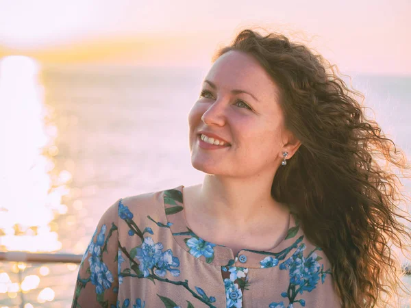 Портрет молодой красивой женщины с вьющимися светлыми волосами, стоящей у моря или океана на восходе солнца — стоковое фото