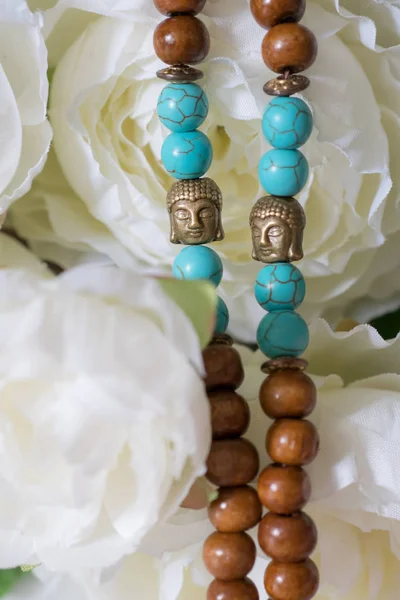 Belles perles de tête en bois et Bouddha avec des pierres précieuses chrysocolla, tourmaline et turquoise sur fond de fleurs. Des perles de mala. chapelet pour la méditation — Photo