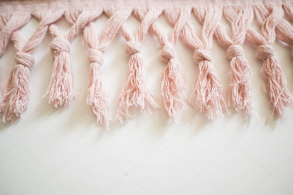 Tassels of a textile on a white background. Pink towel.
