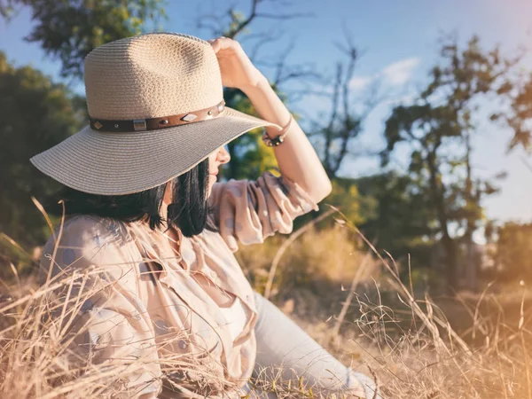 Літній портрет молодої жінки-хіпстера, що лежить у траві в сонячний день. Жінка в капелюсі, концепція кіно, гарне обличчя, мрія, привабливий, мандрівник, відпочинок, мислення, ковбойська леді — стокове фото