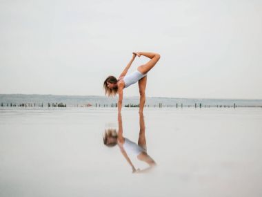 Pratik yoga su liman, göl veya nehir mayo genç beyaz kadın. Güzel yansıması. Karmaşık asanas, denge. Fitness, spor, yoga ve sağlıklı yaşam konsepti.