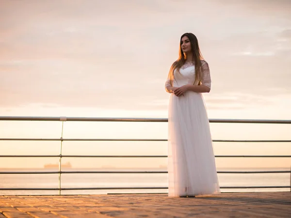 海のそばの白いドレスの空を背景に美少女。美しい花嫁、モデルの目は、ビーチの結婚式の日の上昇。ウェディング ドレス、アパレルの海風を開発. — ストック写真