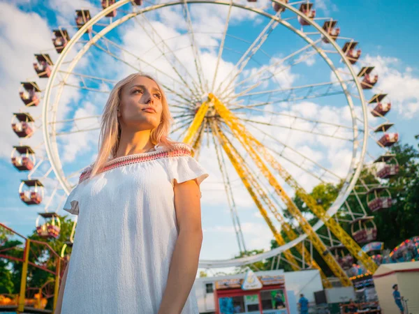 Młody atrakcyjny blond dziewczyna stojący w pobliżu Diabelski Młyn park rozrywki. Piękny portret kobiety z długimi włosami. — Zdjęcie stockowe