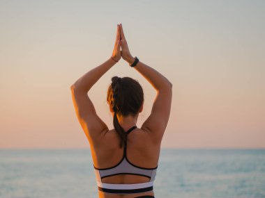 Bir ahşap balkon ya da denize bakan köprü doğada Yoga asana yaparken genç beyaz kadın. Kadının doğada rahatlatıcı okyanus üzerinde pratik yapması. Kız spor giyim.