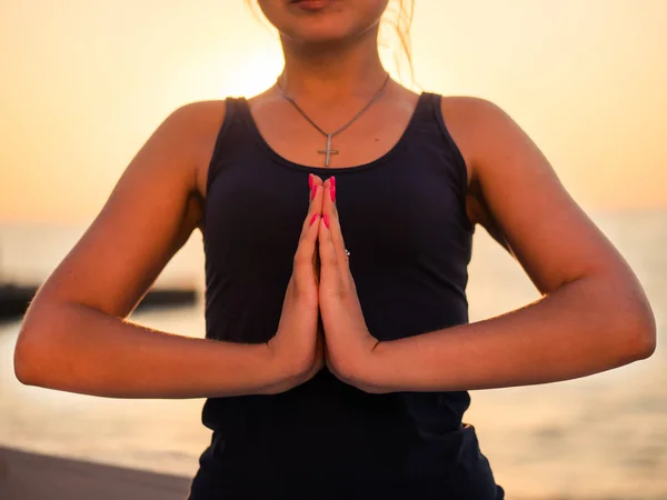 Ritratto di bella donna in abbigliamento sportivo che pratica yoga con namaste, medita, respira, si rilassa seduta in posizione di preghiera sulla spiaggia dell'oceano, vicino all'acqua. Concetto religioso — Foto Stock