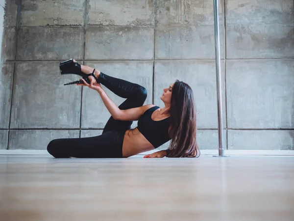 Joven sexy mujer delgada pole bailando en el interior gris. Hermosa, Muchacha atractiva realizando pole dance. Disparo con fondo de hormigón industrial.Dama con buena figura bailando sobre pilón — Foto de Stock