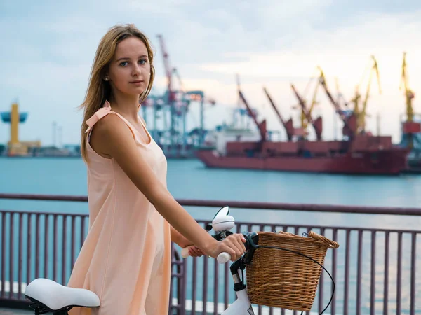 Portrait de mode en plein air d'une élégante dame blonde chevauchant son vélo rétro hipster en robe vintage élégante. Profitez de la journée d'été, posant au port maritime. Mode de vie décontracté. Fille souriante . — Photo