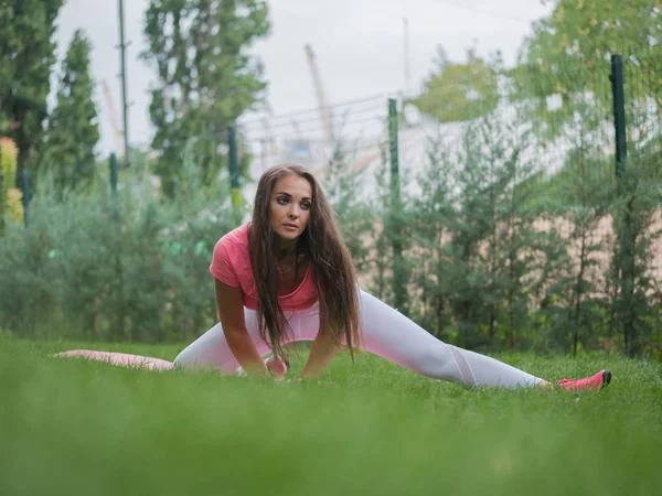 Vacker ung kaukasisk kvinna i fitnesscenter slitage arbetande ute i en park. Kvinna med långt hår och sexig outfit gör sport övningar i skogen på sommaren. — Stockfoto