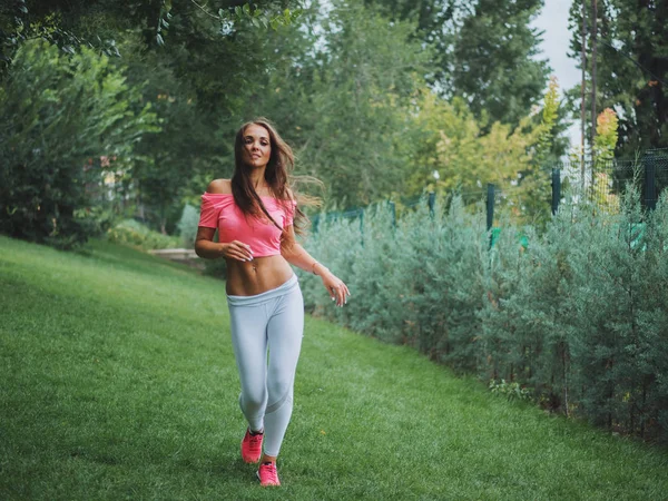 Güzel genç Kafkas kadın fitness aşınmaya bir parkta çalışma dışarı. Bayan uzun saçlı, seksi kıyafeti spor egzersizleri, ormanda bulunan ve yaz aylarında çalıştıran yapıyor.