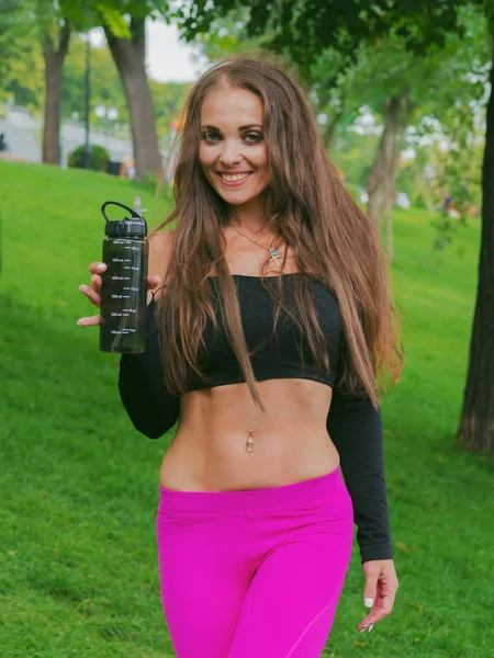 Szomjas nő kocogó edzés után friss ivóvíz. Fiatal szexi sportos nő gyakorolják a parkban szabadban. — Stock Fotó