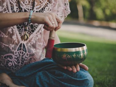 Tibet şarkı kase doğada oynamaya bir kadının elleri. Vintage tarzı. Japa mala, yaz parkta meditasyon yoga mat ile güzel kız.