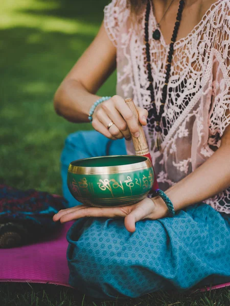 Mains d'une femme jouant au bol de chant tibétain dans la nature. Style vintage. Belle fille avec japa mala, tapis de yoga méditant dans le parc en été . — Photo