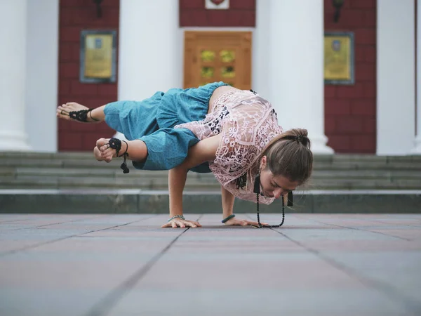 Young beautiful woman in pants alladin practicing yoga colplex asanas in the city in the morning in summer. — Stock Photo, Image