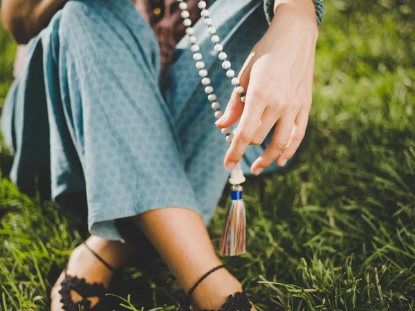 女性は、点灯数マラス、マントラ瞑想中にカウントを維持するために使用される木製のビーズのストランドを閉じ手。仏教。夏の公園で座っている女の子. — ストック写真
