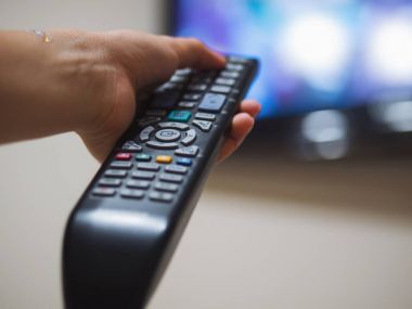 Kanepede televizyon izlerken kız. Genç kadın televizyon uzaktan kumanda ile açar. Sadece el