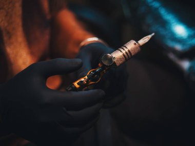 Dövme makinesi koyu arka plan üzerinde tutan Tattooartist.