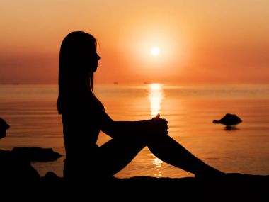 Gün batımı, seksi bir kadın silueti. Tatil, gündoğumu veya günbatımı kum plajı üzerinde oturan kız bikini seyahat sillhouette. Tropikal plaj ince seksi vücut bayanla. Lüks hedef