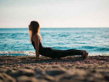 Deniz kum plaj sabah yoga uygulamak güzel ve genç birbayan. Surya Namaskar - güneş selamlar.