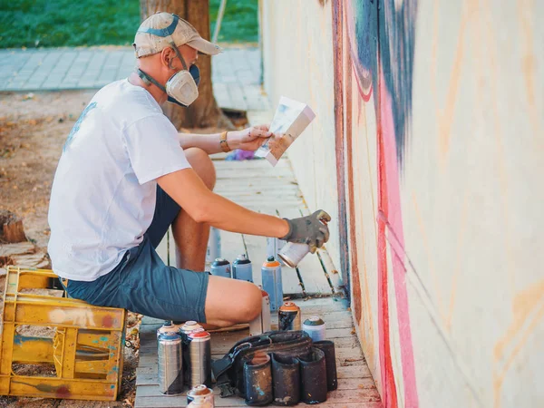 Sokak duvar grafiti sanatçısı resim. Aerosol püskürtülen ilaç şişe duvarının yakınında olan adam. Koruyucu maske renkli aslan çizim genç yetenekli adam.