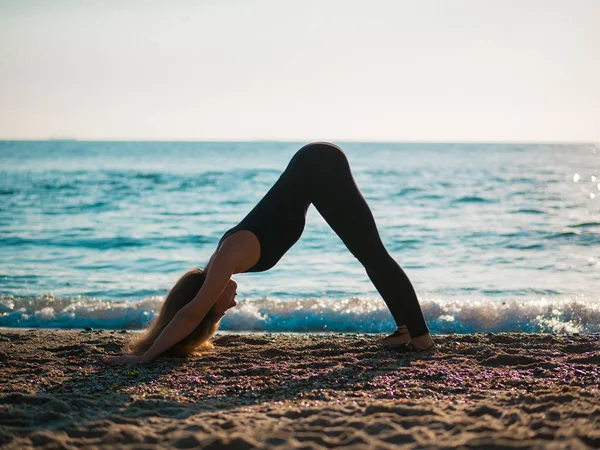 Bella giovane donna che pratica yoga mattutino sulla spiaggia di sabbia del mare. Surya Namaskar - Saluti al sole . — Foto Stock