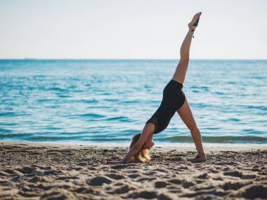 Deniz kum plaj sabah yoga uygulamak güzel ve genç birbayan. Surya Namaskar - güneş selamlar.