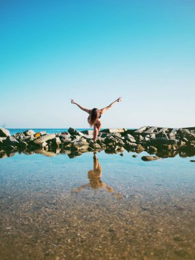 Pratik yoga deniz suyu, göl veya nehir mayo genç beyaz kadın. Güzel yansıması. Karmaşık asanas, denge. Fitness, spor, yoga ve sağlıklı yaşam konsepti.
